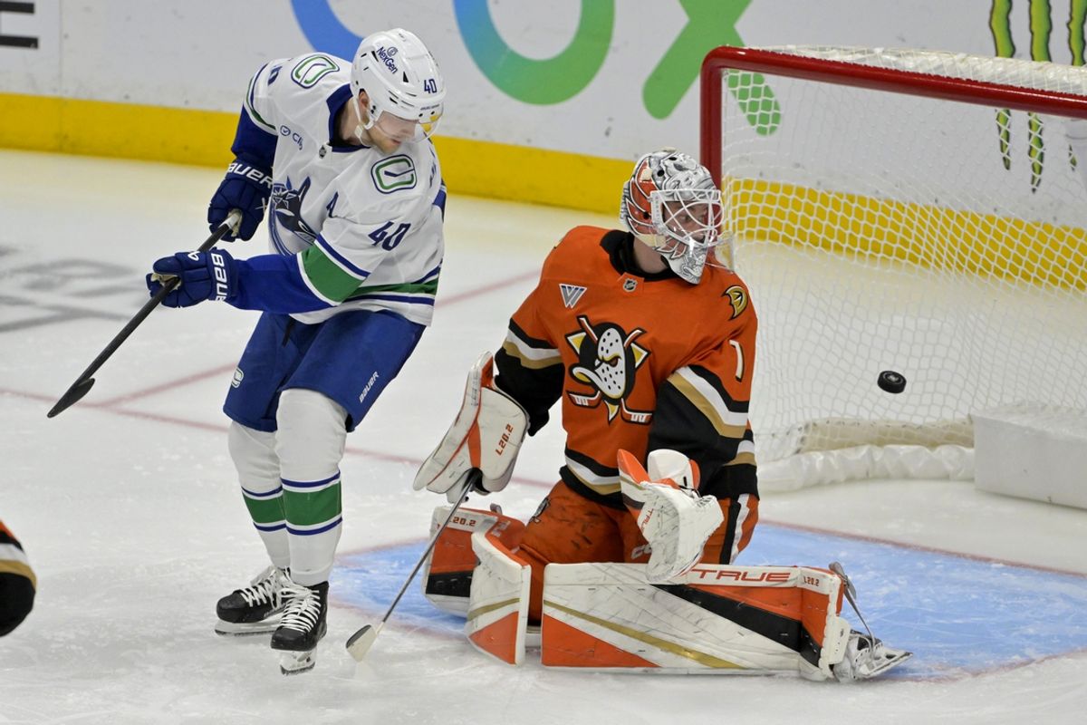 Nov 5, 2024; Anaheim, California, USA; The puck flies past Vancouver Canucks center Elias Pettersson (40) and Anaheim Ducks goaltender Lukas Dostal (1) for a score by Vancouver Canucks defenseman Quinn Hughes (43) in the second period shot by  at Honda Center. Mandatory Credit: Jayne Kamin-Oncea-Imagn Images