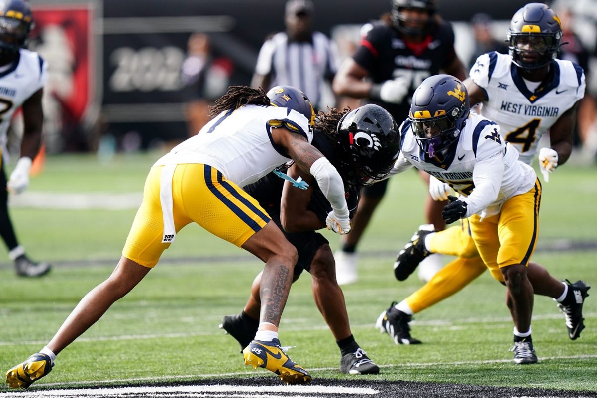 West Virginia Mountaineers cornerback Garnett Hollis Jr. (1) and West Virginia Mountaineers safety Anthony Wilson Jr. (12) tackle Cincinnati Bearcats wide receiver Jamoi Mayes (10) in the first quarter of a college football game between the Cincinnati Bearcats and West Virginia Mountaineers, Saturday, Nov. 9, 2024, at Nippert Stadium in Cincinnati.