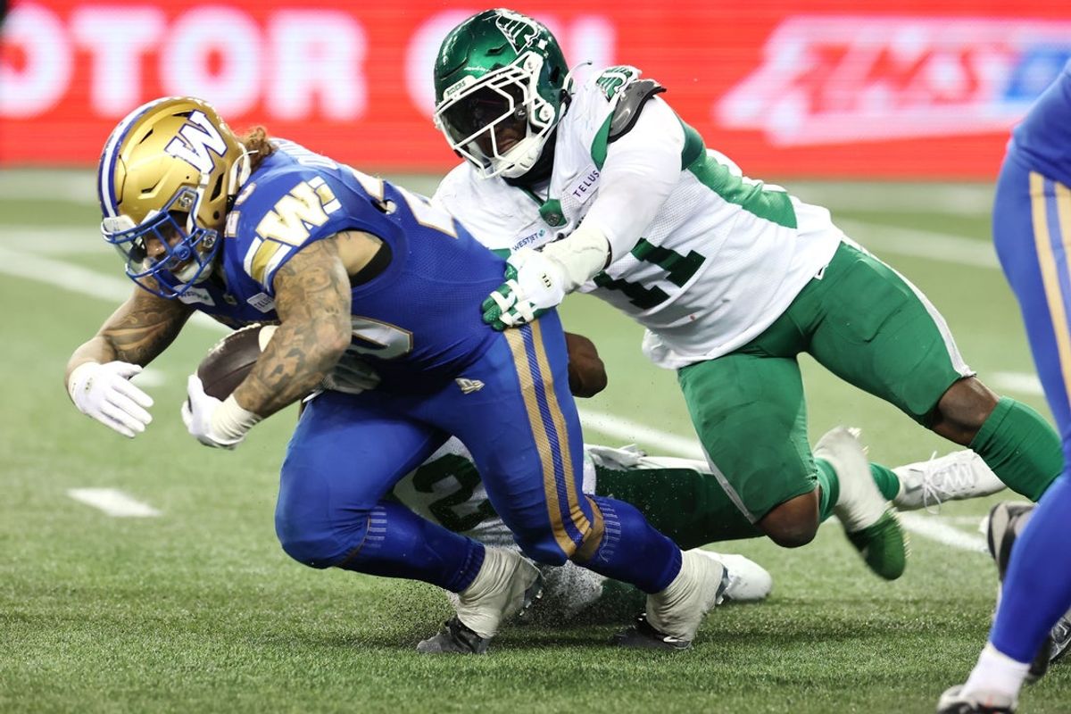 Nov 9, 2024; Winnipeg, Manitoba, CAN;  Winnipeg Blue Bombers running back Brady Oliveira (20) is tackled from behind by Saskatchewan Roughriders defensive end Malik Carney (11) during the second half at PRINCESS AUTO STADIUM. Winnipeg won 38-22. Mandatory Credit: Bruce Fedyck-Imagn Images