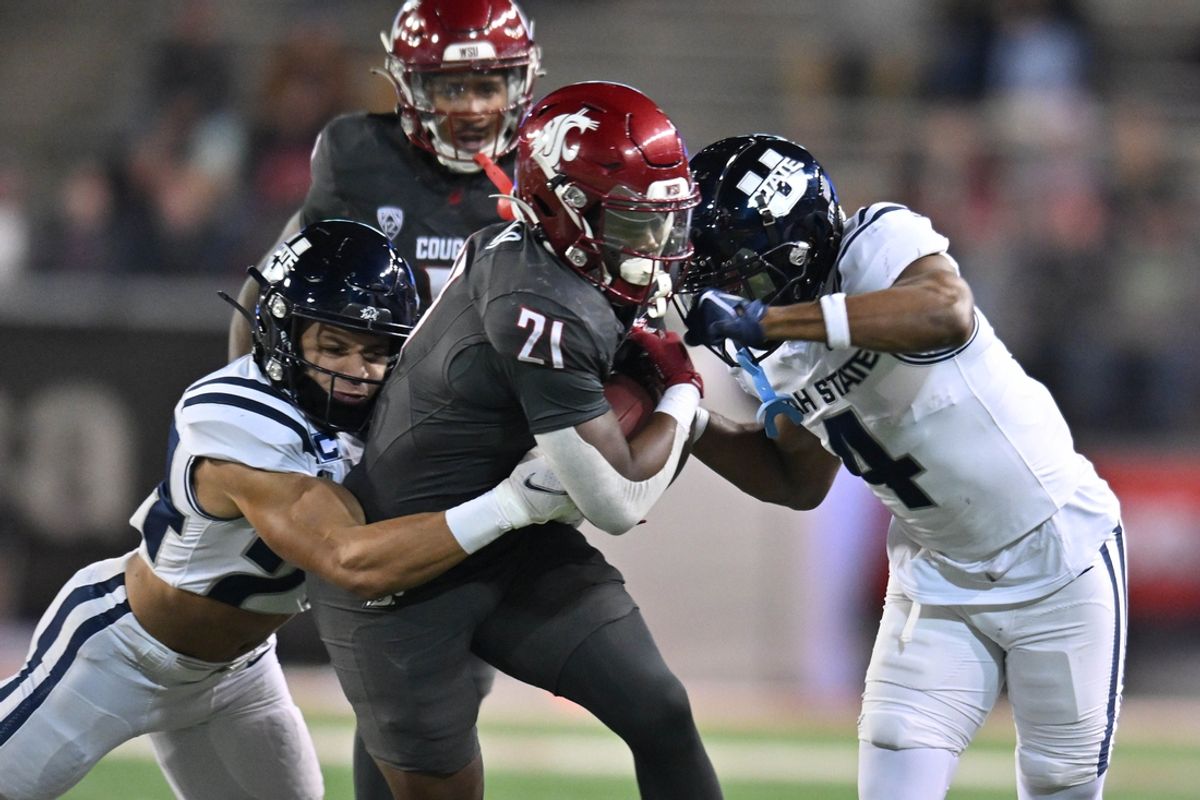 Nov 9, 2024; Pullman, Washington, USA; Washington State Cougars running back Wayshawn Parker (21) is tackled by Utah State Aggies safety Jordan Vincent (24) and cornerback D.J. Graham II (4) in the first half at Gesa Field at Martin Stadium. Mandatory Credit: James Snook-Imagn Images