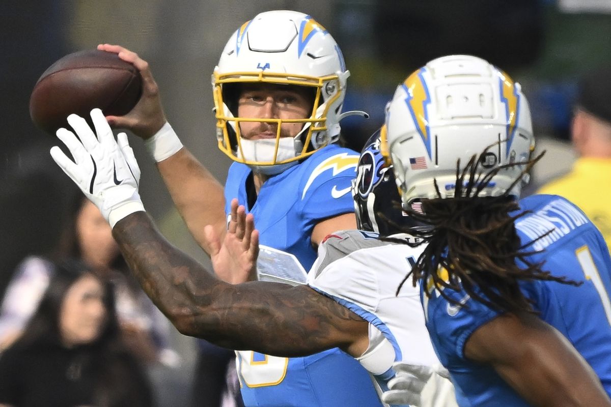 Nov 10, 2024; Inglewood, California, USA; Los Angeles Chargers quarterback Justin Herbert (10) throws a pass under pressure by Tennessee Titans offensive tackle JC Latham (55) during the first quarter at SoFi Stadium. Right is Los Angeles Chargers wide receiver Quentin Johnston (1). Mandatory Credit: Robert Hanashiro-Imagn Images