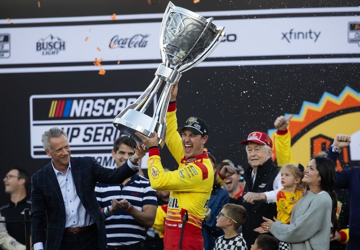 Nov 10, 2024; Avondale, Arizona, USA; NASCAR Cup Series driver Joey Logano (right) is presented the Bill France Trophy by NASCAR president Steve Phelps after winning the 2024 NASCAR Cup Series championship and the NASCAR Cup Series Championship race at Phoenix Raceway. Mandatory Credit: Mark J. Rebilas-Imagn Images