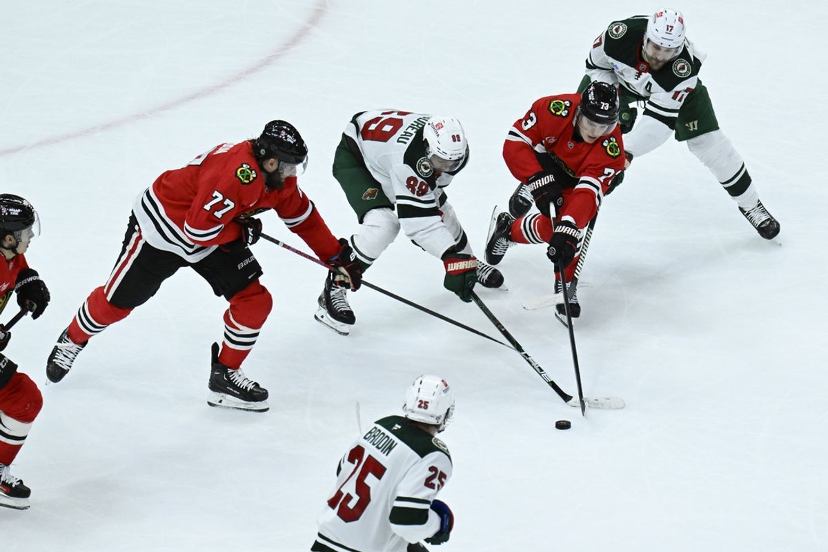 Nov 10, 2024; Chicago, Illinois, USA;  Chicago Blackhawks left wing Lukas Reichel (73) moves the puck past Minnesota Wild left wing Marcus Foligno (17) and center Frederick Gaudreau (89) during the second period at the United Center. Mandatory Credit: Matt Marton-Imagn Images