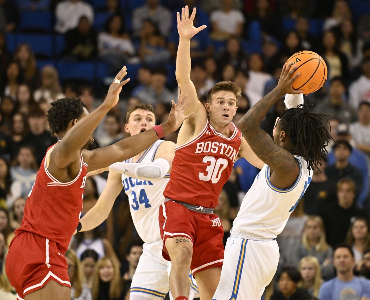 Nov 11, 2024; Los Angeles, California, USA; UCLA Bruins guard Sebastian Mack (right) looks to pass the ball as Boston University Terriers guard Ben Roy (30) defends during the first half at Pauley Pavilion presented by Wescom. Left is UCLA Bruins forward Tyler Bilodeau (34) and Boston University Terriers forward Malcolm Chimezie (3). Mandatory Credit: Robert Hanashiro-Imagn Images