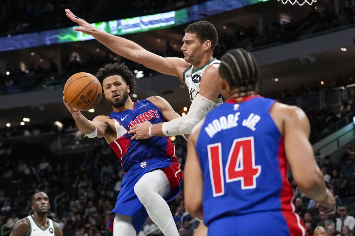 Nov 13, 2024; Milwaukee, Wisconsin, USA;  Detroit Pistons guard Cade Cunningham (2) passes the ball around Milwaukee Bucks center Brook Lopez (11) during the fourth quarter at Fiserv Forum. Mandatory Credit: Jeff Hanisch-Imagn Images