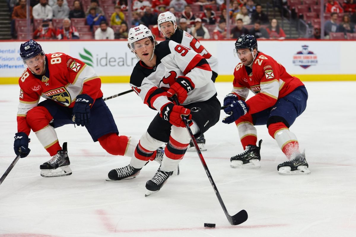 Nov 14, 2024; Sunrise, Florida, USA; New Jersey Devils center Dawson Mercer (91) moves the puck against Florida Panthers defenseman Nate Schmidt (88) and defenseman Uvis Balinskis (26) during the first period at Amerant Bank Arena. Mandatory Credit: Sam Navarro-Imagn Images