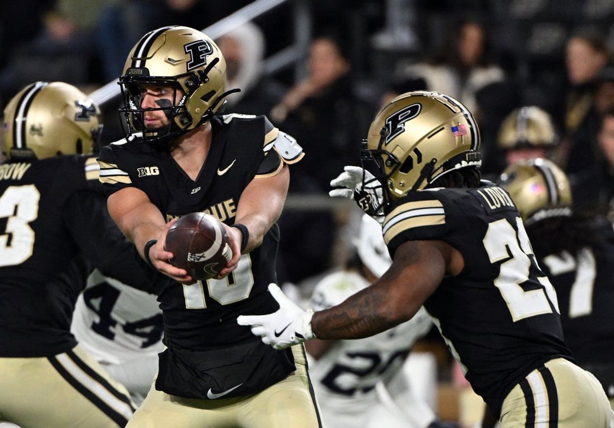 Nov 16, 2024; West Lafayette, Indiana, USA; Purdue Boilermakers quarterback Ryan Browne (15) hands the ball off to running back Reggie Love III (23) during the second half against the Penn State Nittany Lions at Ross-Ade Stadium. Mandatory Credit: Marc Lebryk-Imagn Images