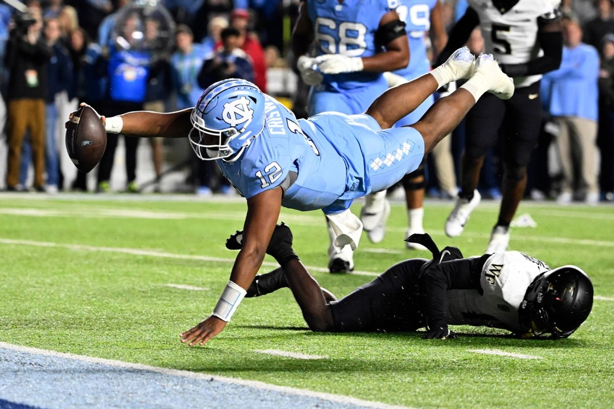 Nov 16, 2024; Chapel Hill, North Carolina, USA; North Carolina Tar Heels quarterback Jacolby Criswell (12) dives for a touchdown as Wake Forest Demon Deacons defensive back Zamari Stevenson (17) defends in the second quarter at Kenan Memorial Stadium. Mandatory Credit: Bob Donnan-Imagn Images