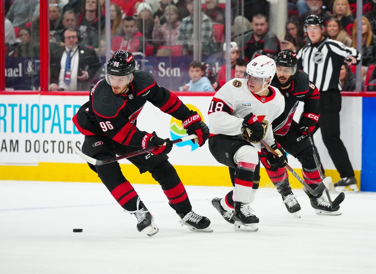 Nov 16, 2024; Raleigh, North Carolina, USA;  Ottawa Senators center Tim Stützle (18) is checked off the puck by Carolina Hurricanes center Jack Roslovic (96) and  defenseman Jalen Chatfield (5) during the second period at Lenovo Center. Mandatory Credit: James Guillory-Imagn Images