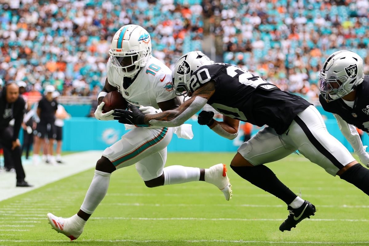 Nov 17, 2024; Miami Gardens, Florida, USA; Miami Dolphins wide receiver Tyreek Hill (10) runs with the football against Las Vegas Raiders safety Isaiah Pola-Mao (20) during the first quarter at Hard Rock Stadium. Mandatory Credit: Sam Navarro-Imagn Images