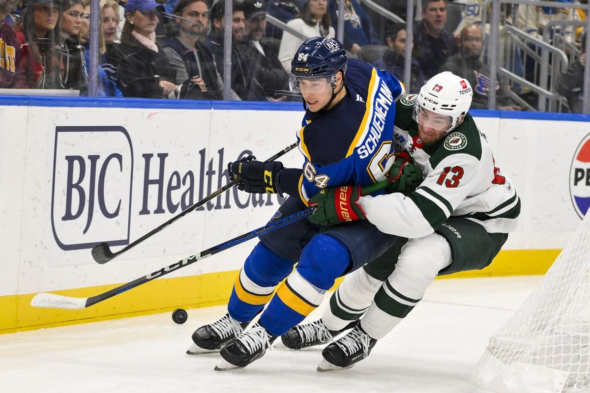 Nov 19, 2024; St. Louis, Missouri, USA;  St. Louis Blues defenseman Corey Schueneman (64) and Minnesota Wild center Yakov Trenin (13) battle for the puck during the first period at Enterprise Center. Mandatory Credit: Jeff Curry-Imagn Images
