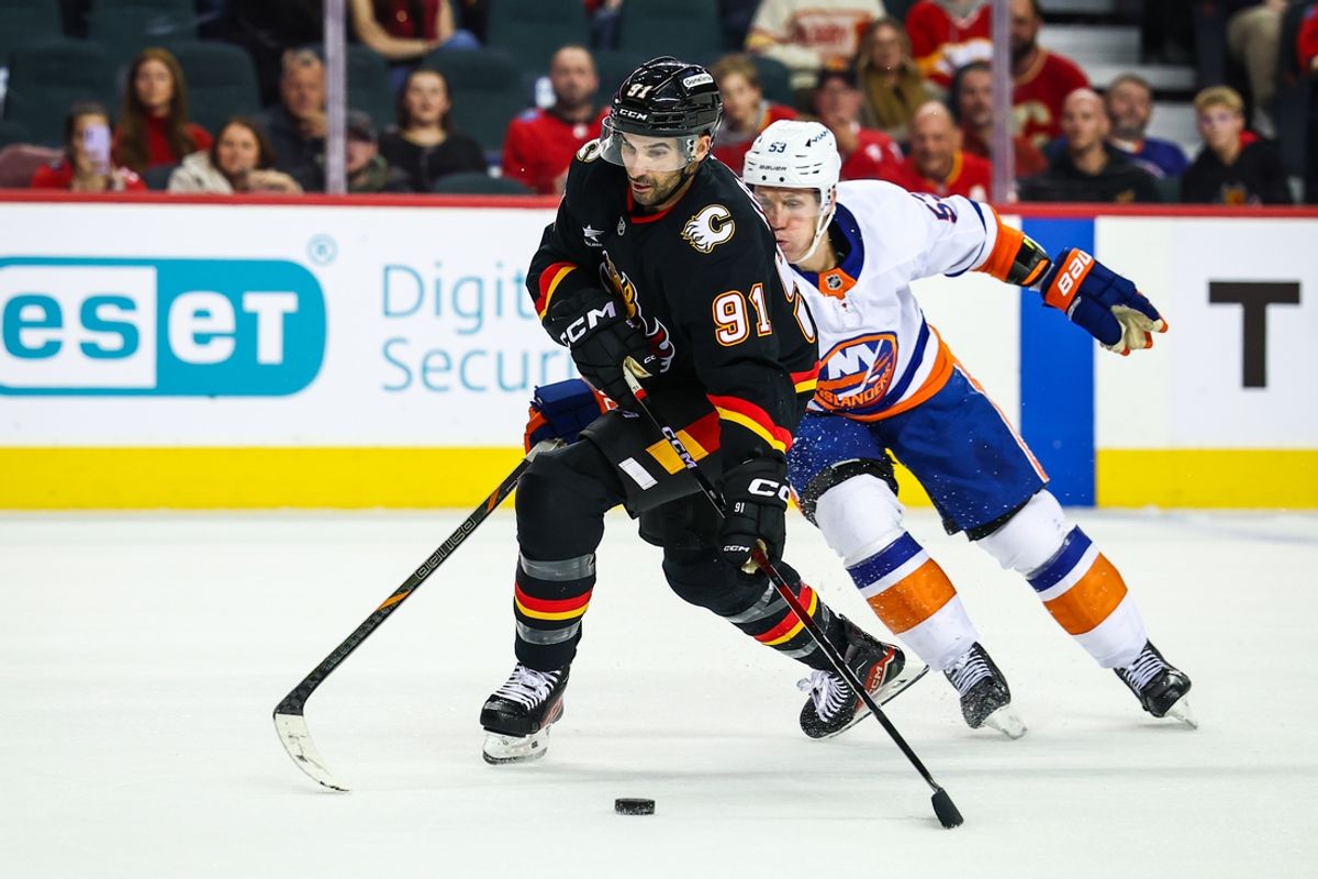 Nov 19, 2024; Calgary, Alberta, CAN; Calgary Flames center Nazem Kadri (91) and New York Islanders center Casey Cizikas (53) battles for the puck during the overtime period at Scotiabank Saddledome. Mandatory Credit: Sergei Belski-Imagn Images