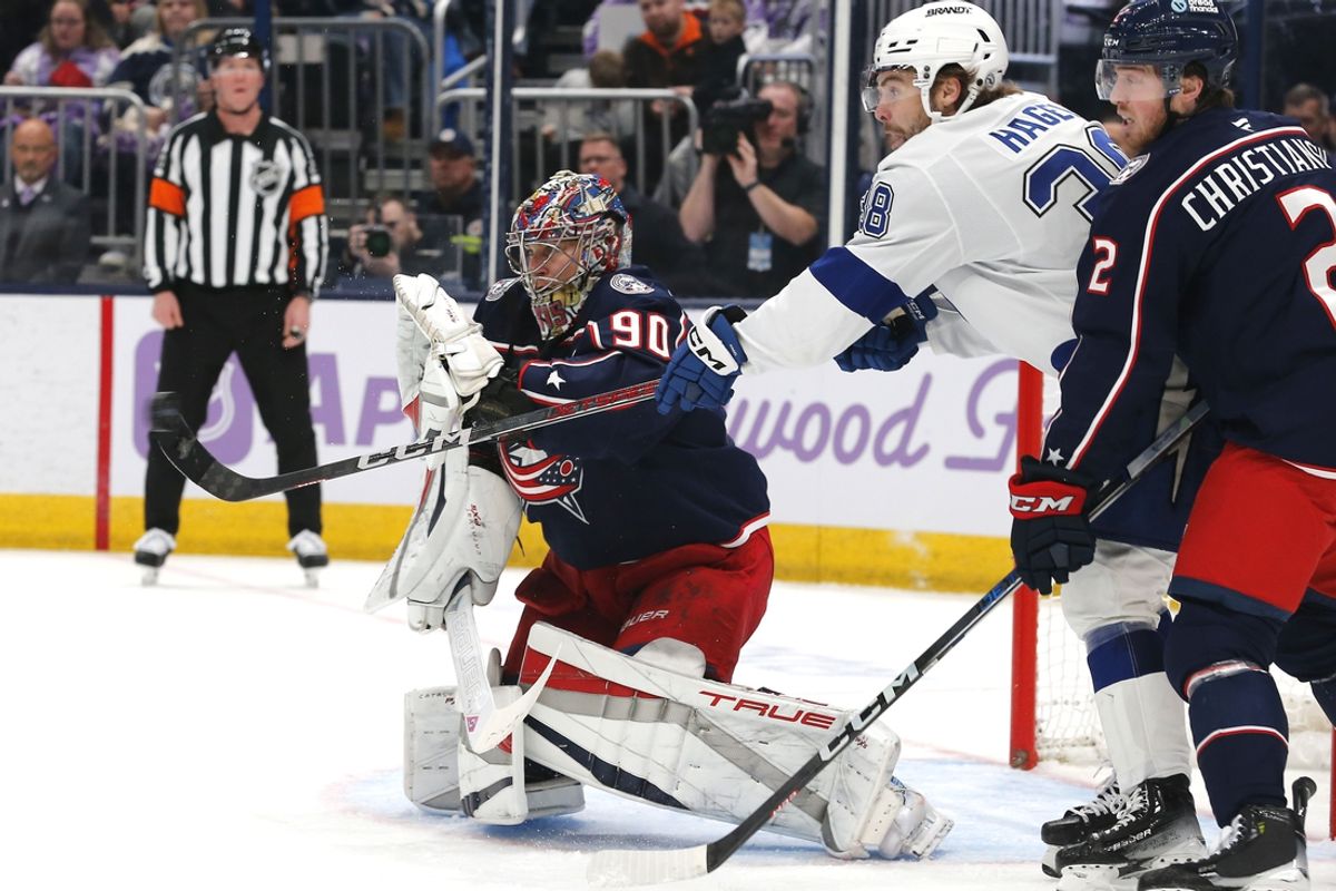 Nov 21, 2024; Columbus, Ohio, USA; Columbus Blue Jackets goalie Elvis Merzlikins (90) makes a glove save as Tampa Bay Lightning left wing Brandon Hagel (38) looks for a rebound during the first period at Nationwide Arena. Mandatory Credit: Russell LaBounty-Imagn Images