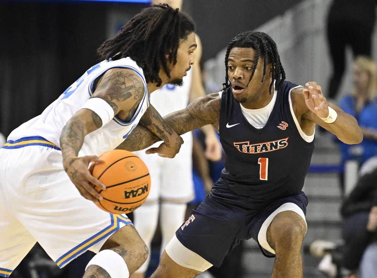 Nov 22, 2024; Los Angeles, California, USA; UCLA Bruins guard Skyy Clark (55) tries to dribble the ball past Cal State Fullerton Titans guard Keith Richard (1) during the first half  at Pauley Pavilion presented by Wescom. Mandatory Credit: Robert Hanashiro-Imagn Images