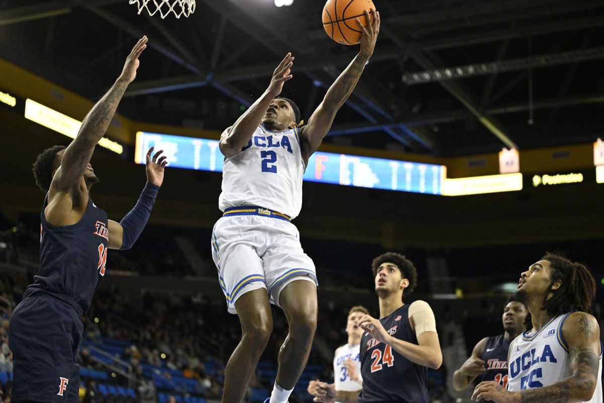 Nov 22, 2024; Los Angeles, California, USA; UCLA Bruins guard Dylan Andrews (2) drives to the basket past Cal State Fullerton Titans guard Antwan Robinson (10) and forward Kendrick De Luna (24) during the second half at Pauley Pavilion presented by Wescom. Mandatory Credit: Robert Hanashiro-Imagn Images
