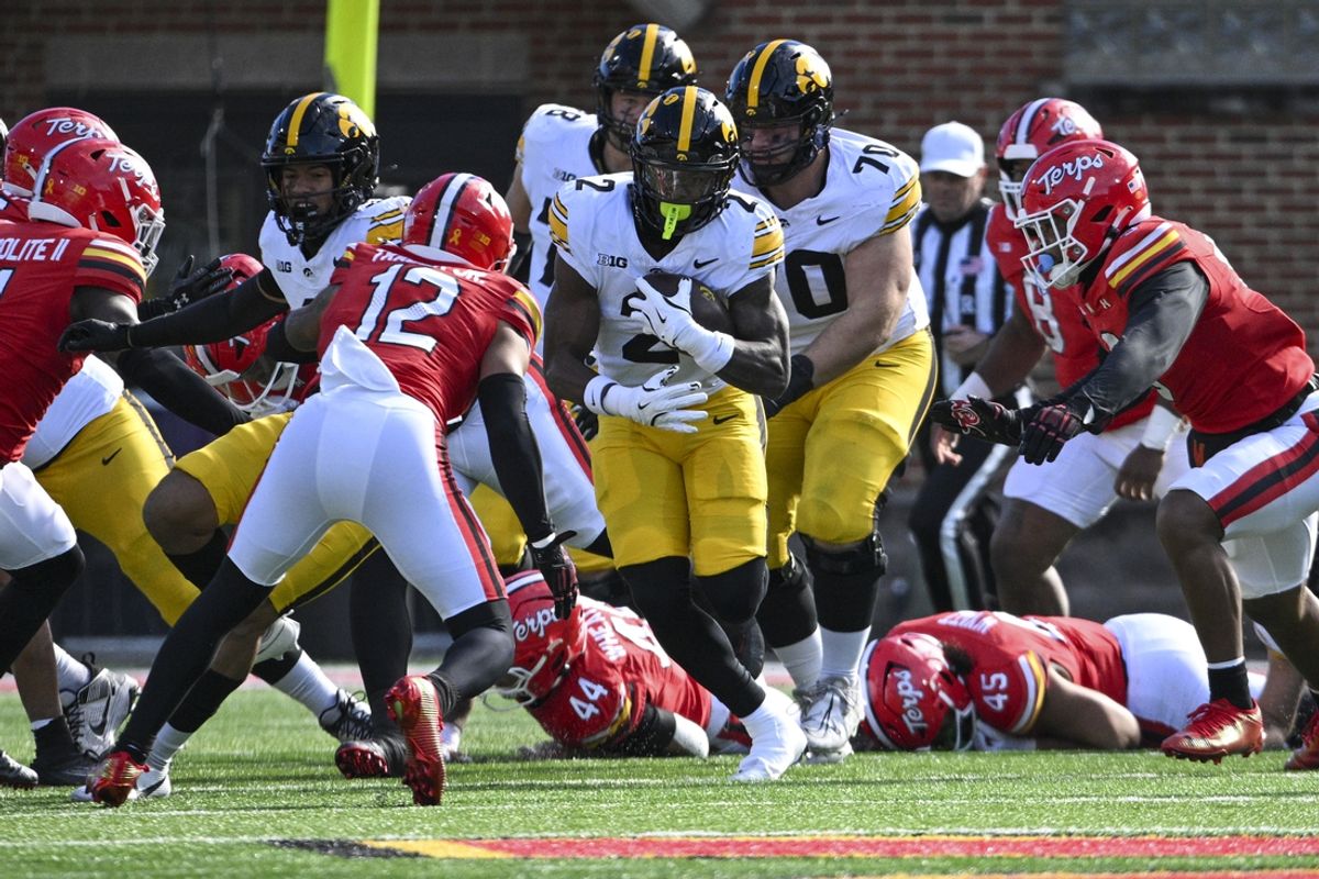 Nov 23, 2024; College Park, Maryland, USA;  Iowa Hawkeyes running back Kaleb Johnson (2) rushes as Maryland Terrapins defensive back Dante Trader Jr. (12) defends during the first half at SECU Stadium. Mandatory Credit: Tommy Gilligan-Imagn Images