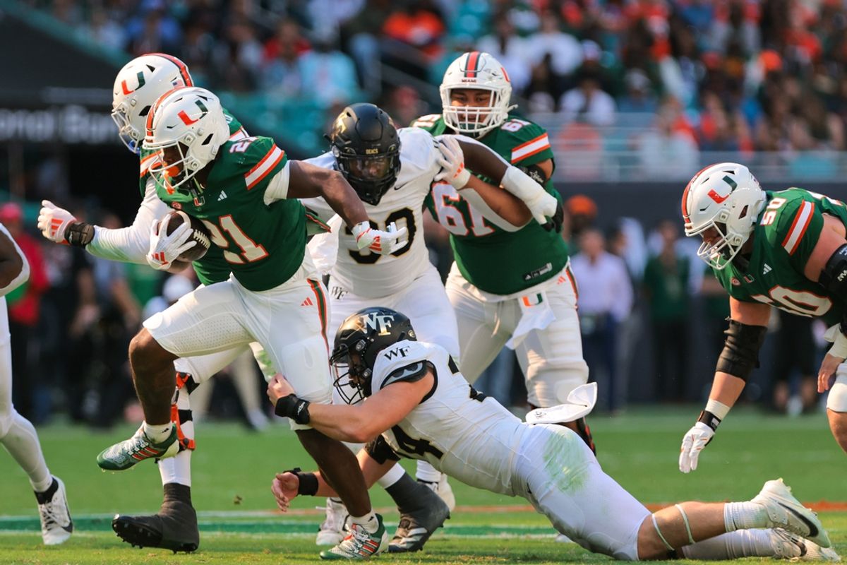 Nov 23, 2024; Miami Gardens, Florida, USA; Miami Hurricanes running back Jordan Lyle (21) run with the football past Wake Forest Demon Deacons linebacker Dylan Hazen (24) during the second quarter at Hard Rock Stadium. Mandatory Credit: Sam Navarro-Imagn Images