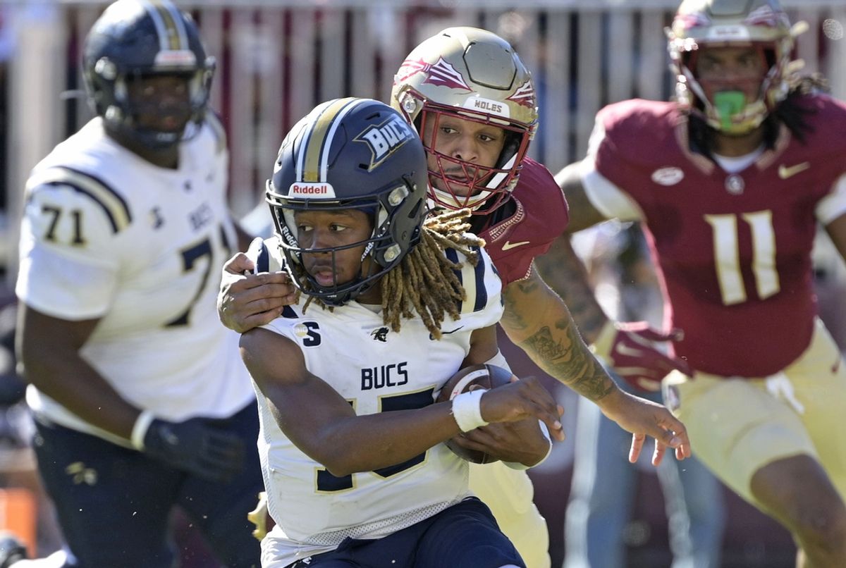 Nov 23, 2024; Tallahassee, Florida, USA; Charleston Southern Buccaneers quarterback Kaleb Jackson (15) is tackled by Florida State Seminoles defensive lineman Byron Turner Jr. (54) during the first quarter at Doak S. Campbell Stadium. Mandatory Credit: Melina Myers-Imagn Images