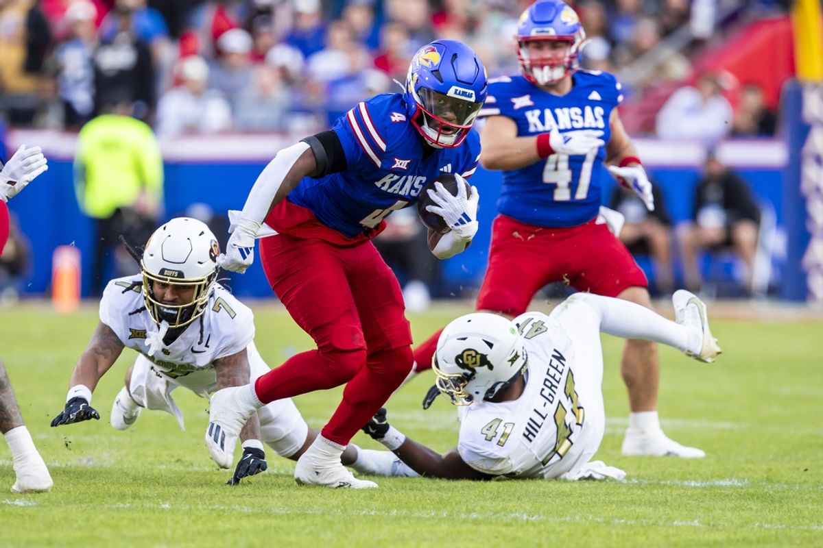 Nov 23, 2024; Kansas City, Missouri, USA;  Kansas running back Devin Neal (4) splits the defense for additional yardage during the 1st quarter between the Kansas Jayhawks and the Colorado Buffaloes at GEHA Field at Arrowhead Stadium. Mandatory Credit: Nick Tre. Smith-Imagn Images
