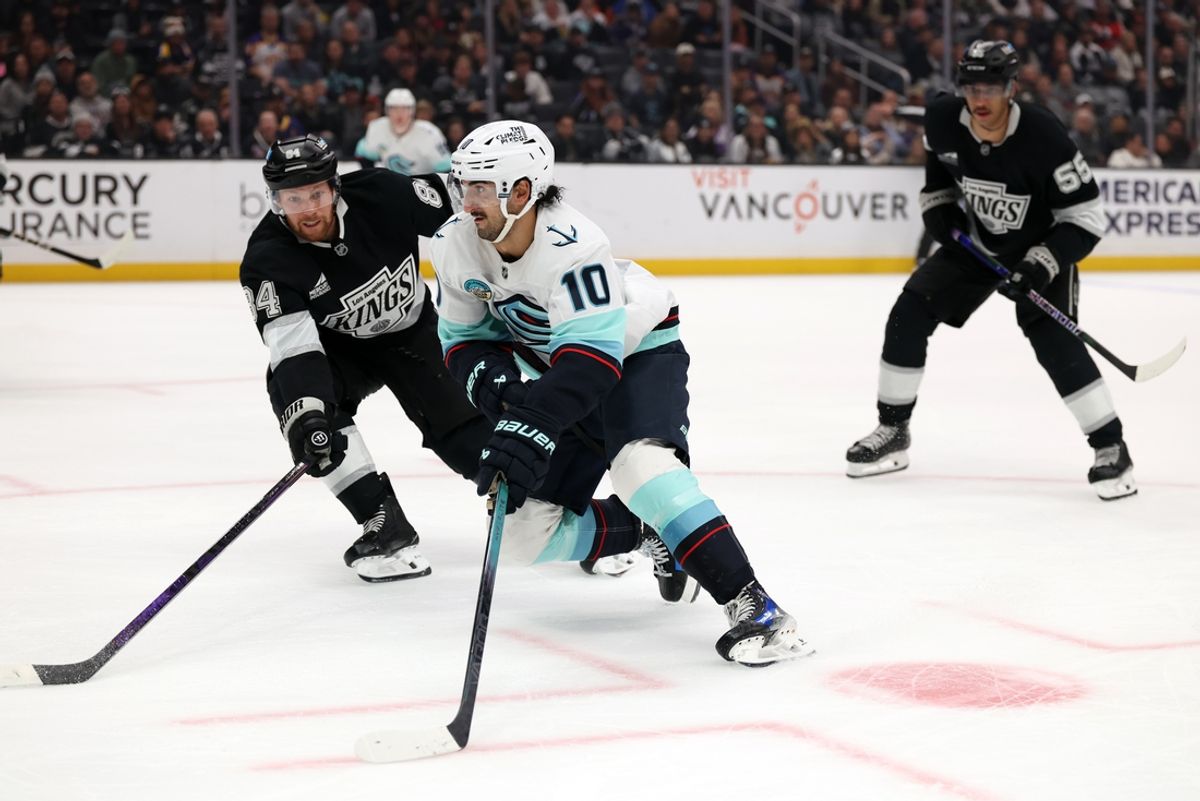 Nov 23, 2024; Los Angeles, California, USA;  Seattle Kraken center Matty Beniers (10) controls the puck against Los Angeles Kings defenseman Vladislav Gavrikov (84) during the third period at Crypto.com Arena. Mandatory Credit: Kiyoshi Mio-Imagn Images