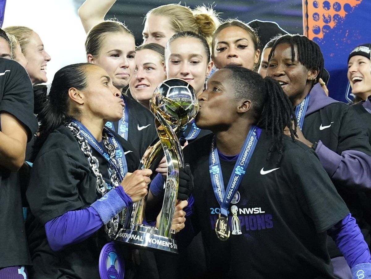 Nov 23, 2024; Kansas City, Missouri, USA;  Orlando Pride forward Marta (10) and Orlando Pride forward Barbra Banda (22) kiss the championship trophy after defeating the Washington Spirit in the 2024 NWSL Championship match at CPKC Stadium. Mandatory Credit: Jay Biggerstaff-Imagn Images