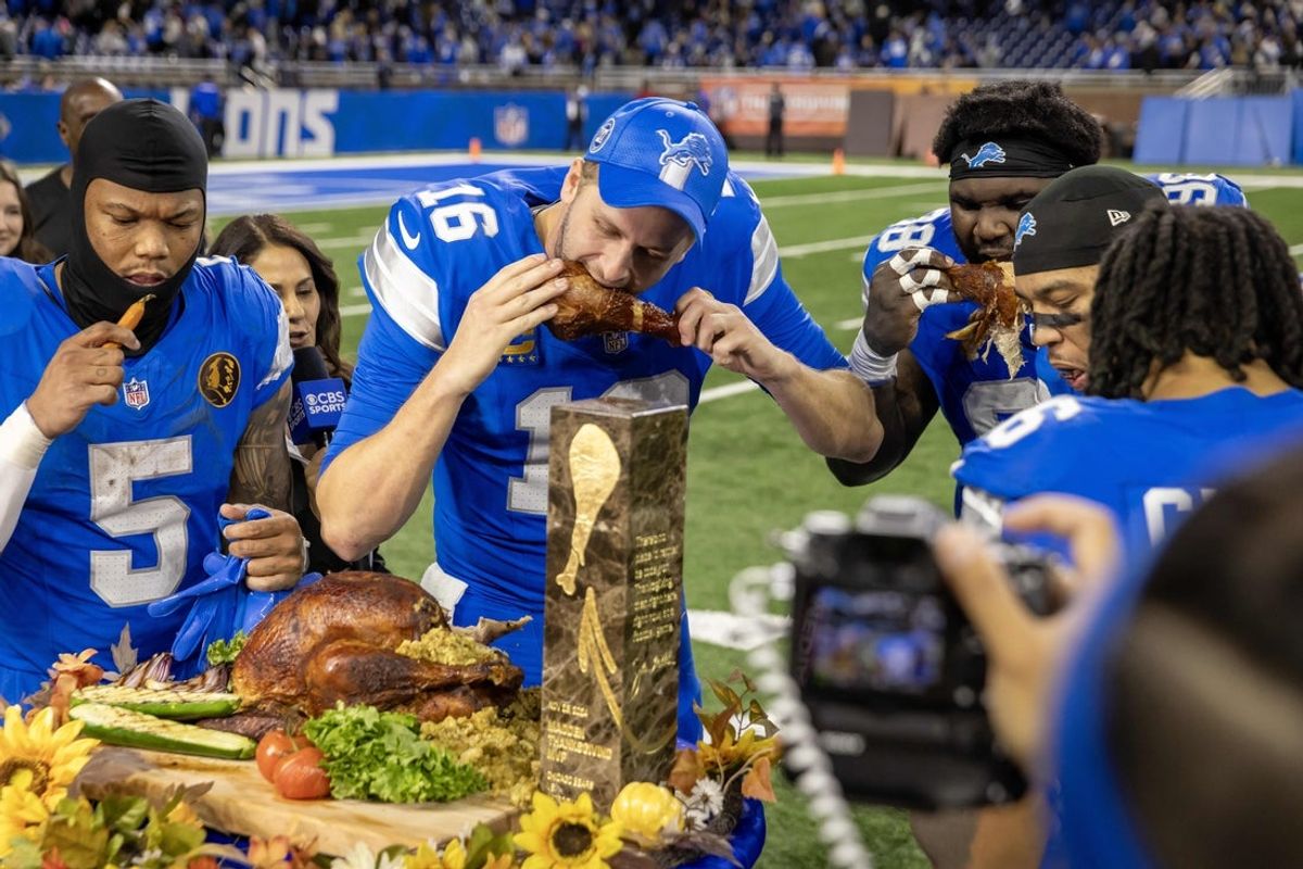 Nov 28, 2024; Detroit, Michigan, USA; Detroit Lions quarterback Jared Goff (16) takes a bite of the John Madden MVP Turkey with teammates after the annual Thanksgiving Day game defeating the Chicago Bears at Ford Field. Mandatory Credit: David Reginek-Imagn Images