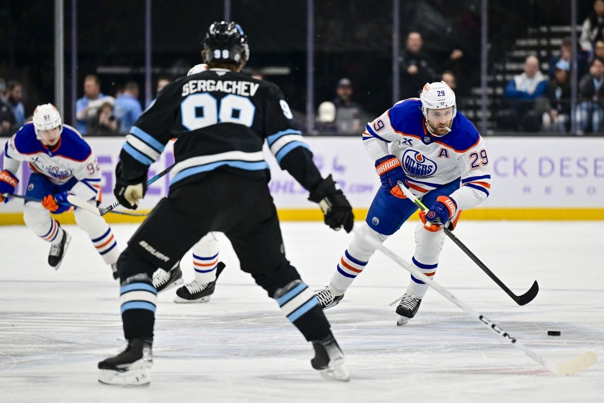 Nov 29, 2024; Salt Lake City, Utah, USA; Edmonton Oilers center Leon Draisaitl (29) moves the puck around Utah Hockey Club defenseman Mikhail Sergachev (98) at the Delta Center. Mandatory Credit: Christopher Creveling-Imagn Images