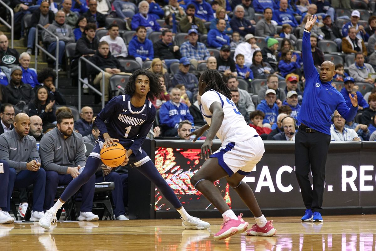 Nov 30, 2024; Newark, New Jersey, USA; Monmouth Hawks guard Abdi Bashir Jr. (1) looks to shoot the ball as Seton Hall Pirates guard Garwey Dual (33) defends in front of head coach Shaheen Holloway during the first half at Prudential Center. Mandatory Credit: Vincent Carchietta-Imagn Images