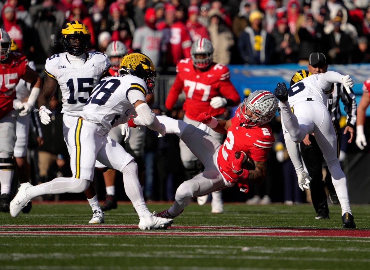 Ohio State Buckeyes wide receiver Emeka Egbuka (2) is updended by Michigan Wolverines defensive back Quinten Johnson (28) and Michigan Wolverines defensive back Brandyn Hillman (6) during the first half of Saturday’s NCAA Division I football game at Ohio Stadium.