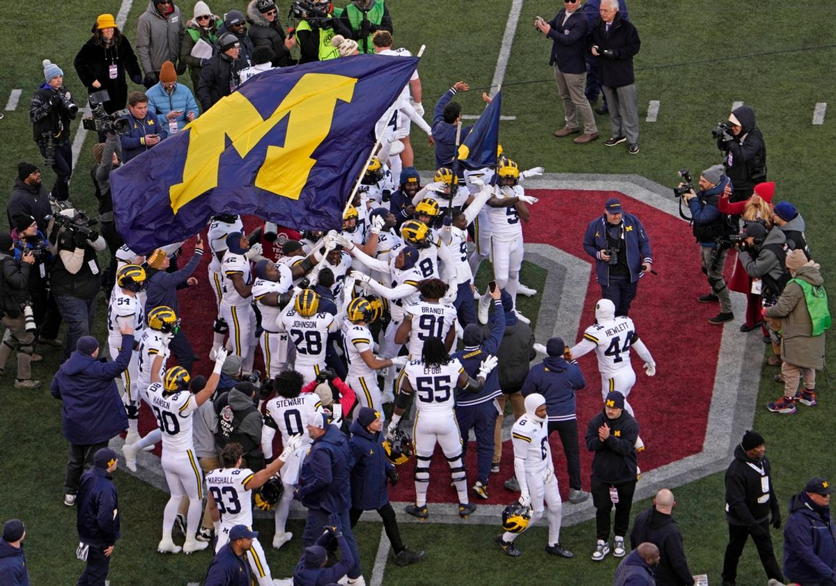 Michigan football players plant their team’s flag at midfield following Saturday’s NCAA Division I football game against the Ohio State Buckeyes at Ohio Stadium. The Michigan Wolverines won the game 13-10.
