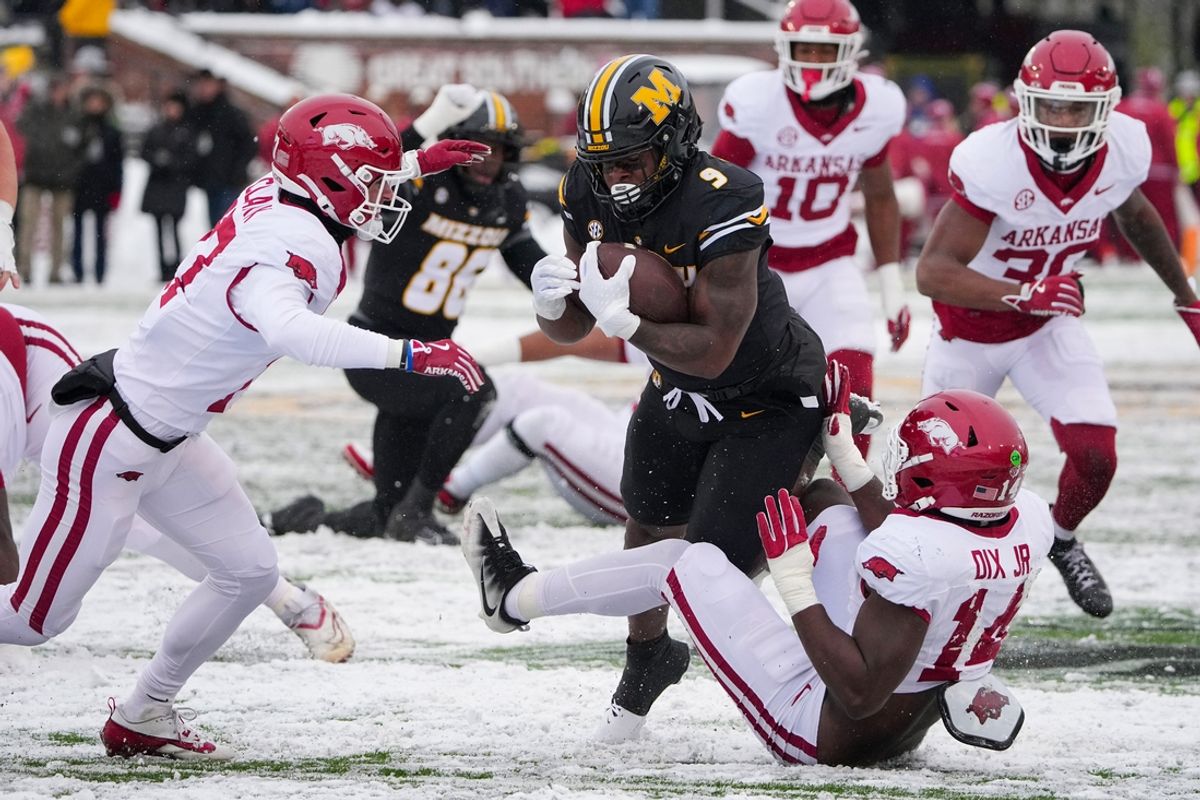 Nov 30, 2024; Columbia, Missouri, USA; Missouri Tigers running back Marcus Carroll (9) runs the ball as Arkansas Razorbacks linebacker Stephen Dix Jr. (14) attempts the tackle during the first half at Faurot Field at Memorial Stadium. Mandatory Credit: Denny Medley-Imagn Images