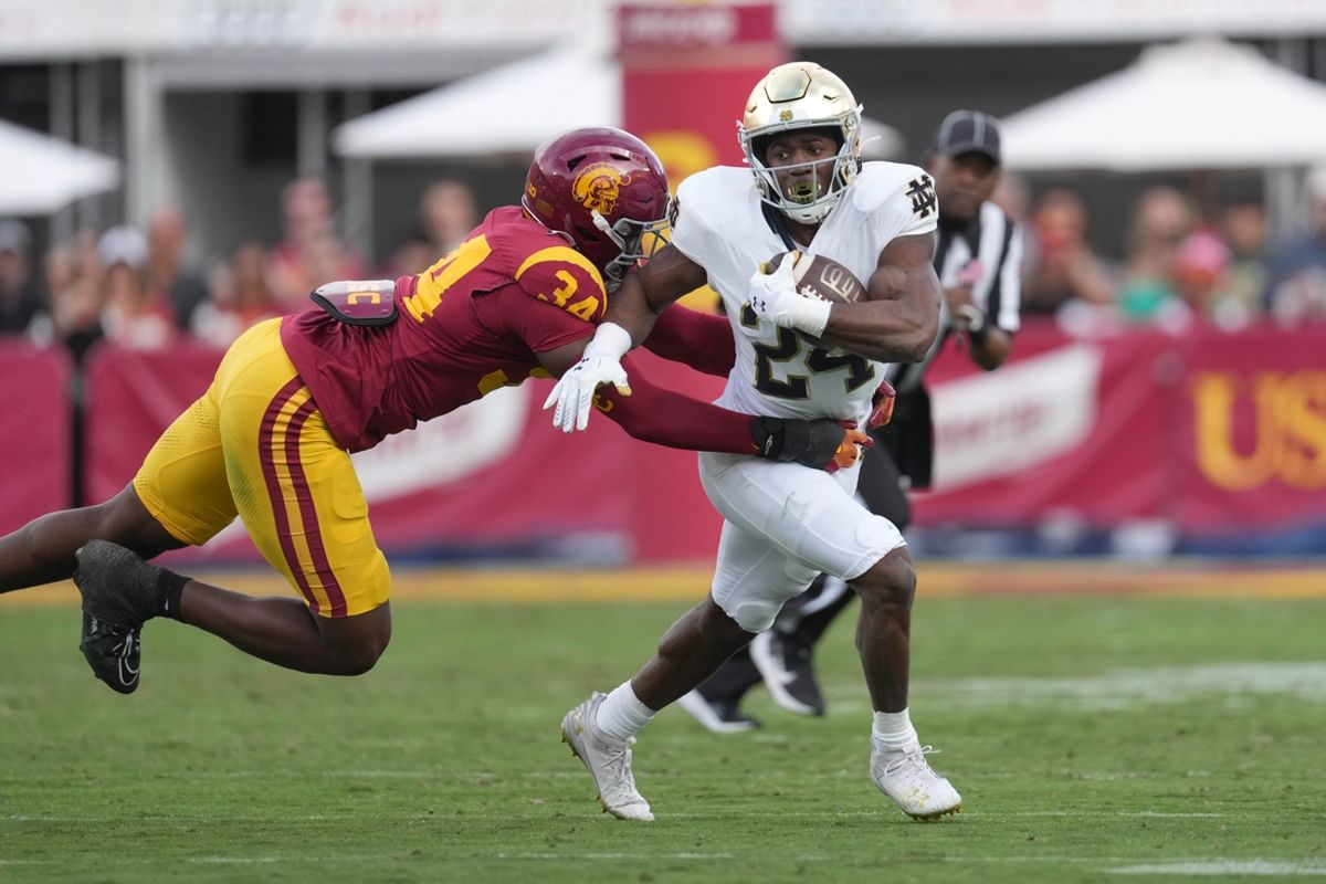 Nov 30, 2024; Los Angeles, California, USA; Notre Dame Fighting Irish running back Jadarian Price (24) carries the ball against Southern California Trojans defensive end Braylan Shelby (34) in the first half at United Airlines Field at Los Angeles Memorial Coliseum. Mandatory Credit: Kirby Lee-Imagn Images