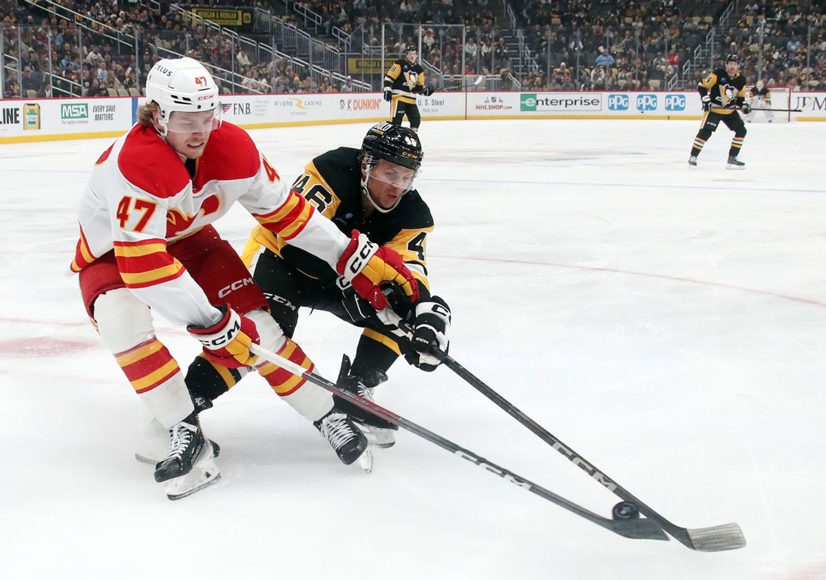 Nov 30, 2024; Pittsburgh, Pennsylvania, USA;  Calgary Flames center Connor Zary (47) and Pittsburgh Penguins center Blake Lizotte (46) play the puck during the first period at PPG Paints Arena. Mandatory Credit: Charles LeClaire-Imagn Images