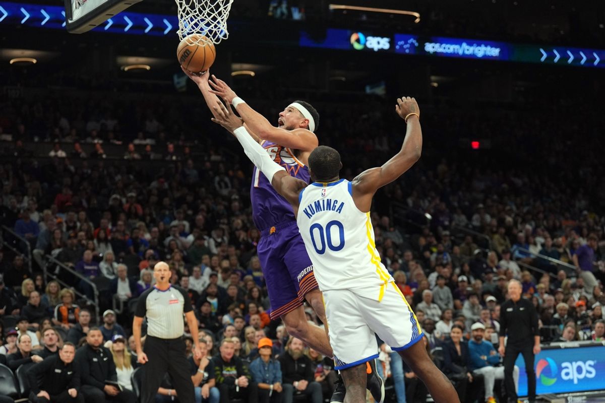 Nov 30, 2024; Phoenix, Arizona, USA; Phoenix Suns guard Devin Booker (1) puts up a layup over Golden State Warriors forward Jonathan Kuminga (00) during the second half at Footprint Center. Mandatory Credit: Joe Camporeale-Imagn Images