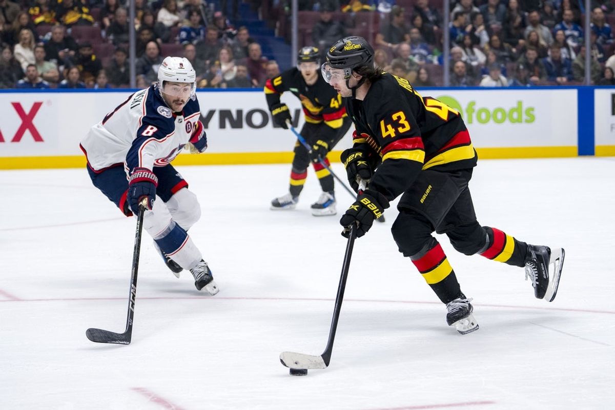 Dec 6, 2024; Vancouver, British Columbia, CAN; Vancouver Canucks defenseman Quinn Hughes (43) skates past Columbus Blue Jackets defenseman Zach Werenski (8) during the second period at Rogers Arena. Mandatory Credit: Bob Frid-Imagn Images
