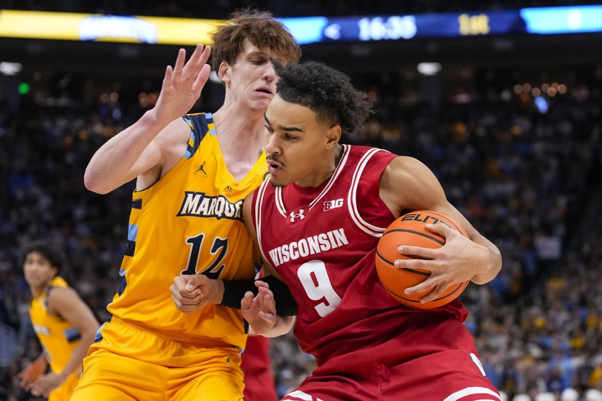 Dec 7, 2024; Milwaukee, Wisconsin, USA;  Wisconsin Badgers guard John Tonje (9) drives for the basket against Marquette Golden Eagles forward Ben Gold (12) during the first half at Fiserv Forum. Mandatory Credit: Jeff Hanisch-Imagn Images
