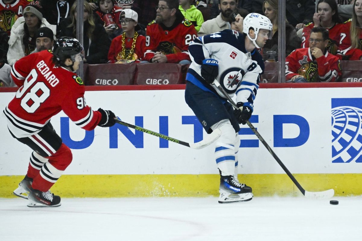 Dec 7, 2024; Chicago, Illinois, USA;  Winnipeg Jets defenseman Josh Morrissey (44) moves the puck against Chicago Blackhawks center Connor Bedard (98) during the first period at United Center. Mandatory Credit: Matt Marton-Imagn Images