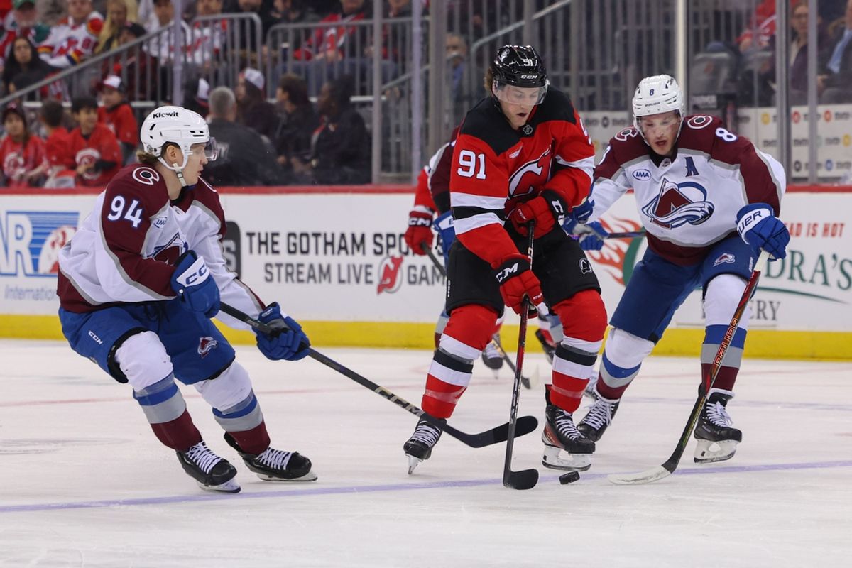 Dec 8, 2024; Newark, New Jersey, USA; New Jersey Devils center Dawson Mercer (91) handles the puck while being defended by Colorado Avalanche left wing Joel Kiviranta (94) and defenseman Cale Makar (8) during the second period at Prudential Center. Mandatory Credit: Ed Mulholland-Imagn Images