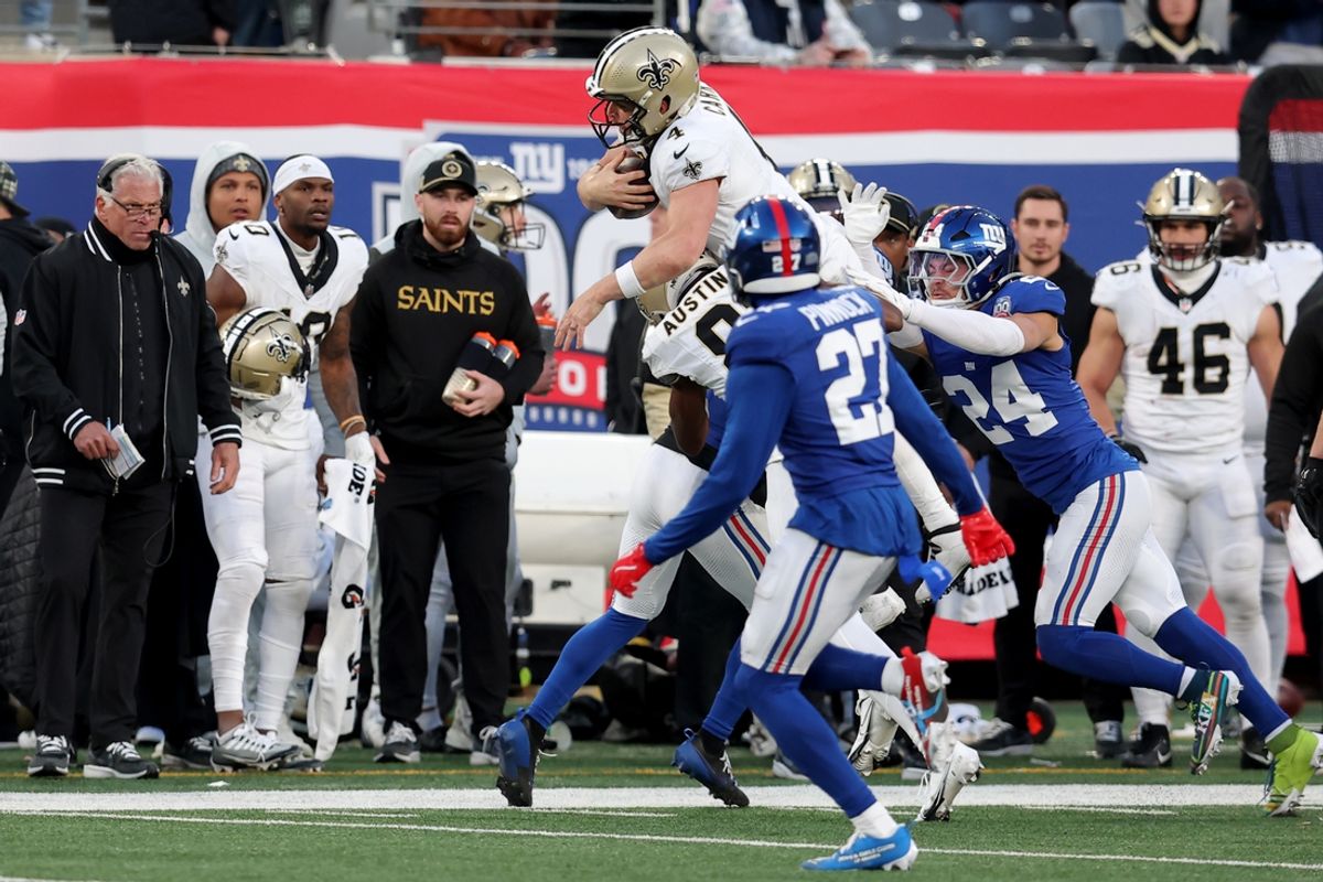Dec 8, 2024; East Rutherford, New Jersey, USA; New Orleans Saints quarterback Derek Carr (4) attempts to leap over New York Giants cornerback Adoree' Jackson (21) and safety Dane Belton (24) during the fourth quarter at MetLife Stadium. Mandatory Credit: Brad Penner-Imagn Images