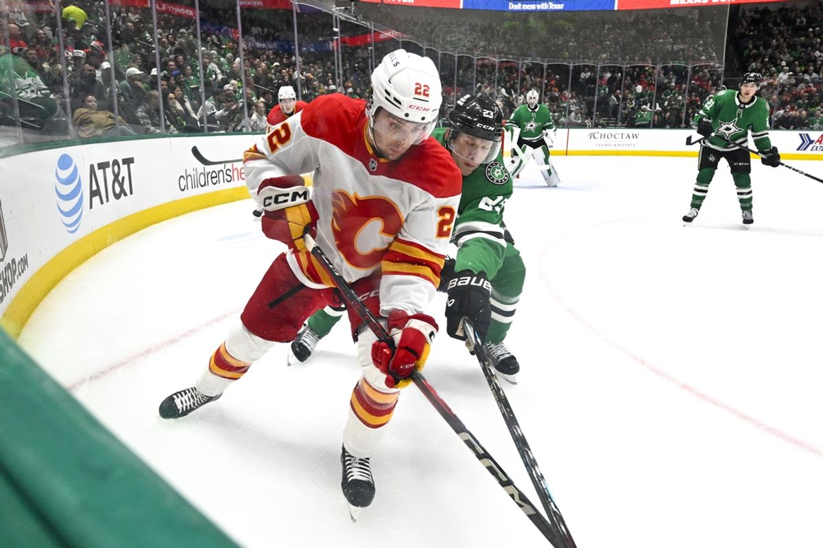 Dec 8, 2024; Dallas, Texas, USA; Calgary Flames center Jakob Pelletier (22) and Dallas Stars defenseman Esa Lindell (23) battle for control of the puck during the third period at the American Airlines Center. Mandatory Credit: Jerome Miron-Imagn Images