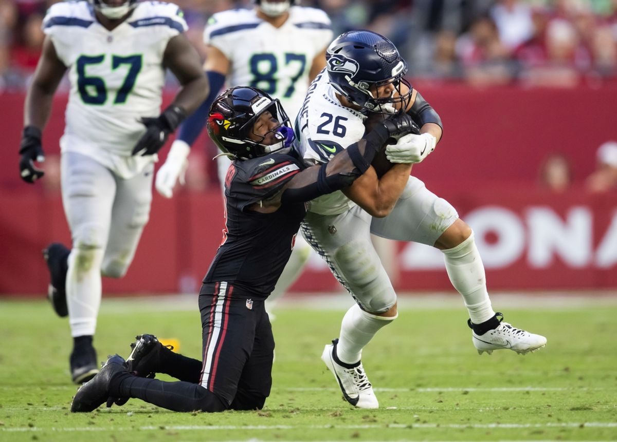 Dec 8, 2024; Glendale, Arizona, USA; Seattle Seahawks running back Zach Charbonnet (26) is tackled by Arizona Cardinals safety Budda Baker (3) at State Farm Stadium. Mandatory Credit: Mark J. Rebilas-Imagn Images
