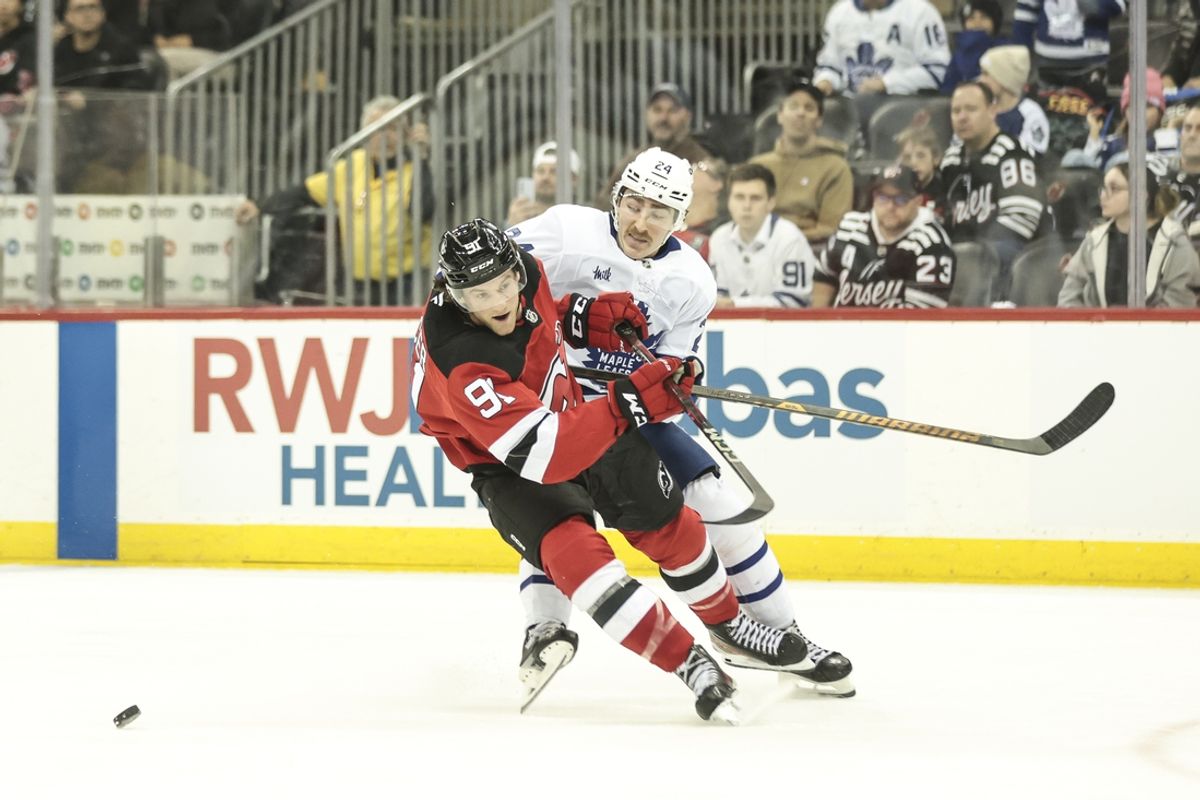 Dec 10, 2024; Newark, New Jersey, USA; New Jersey Devils center Dawson Mercer (91) and Toronto Maple Leafs center Connor Dewar (24) fight for the puck during the third period at Prudential Center. Mandatory Credit: Luther Schlaifer-Imagn Images