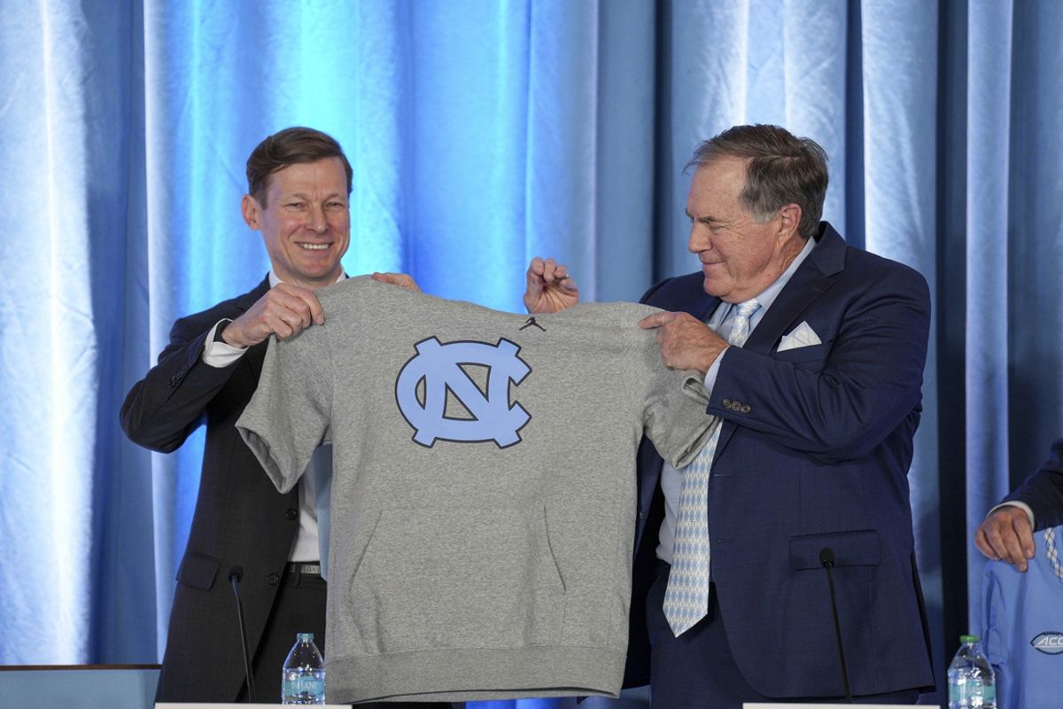 Dec 12, 2024; Chapel Hill, NC, USA;  North Carolina Tar Heels chancellor Lee Roberts presents a cut off sweatshirt to new head coach Bill Belichick at Loudermilk Center for Excellence. Mandatory Credit: Jim Dedmon-Imagn Images