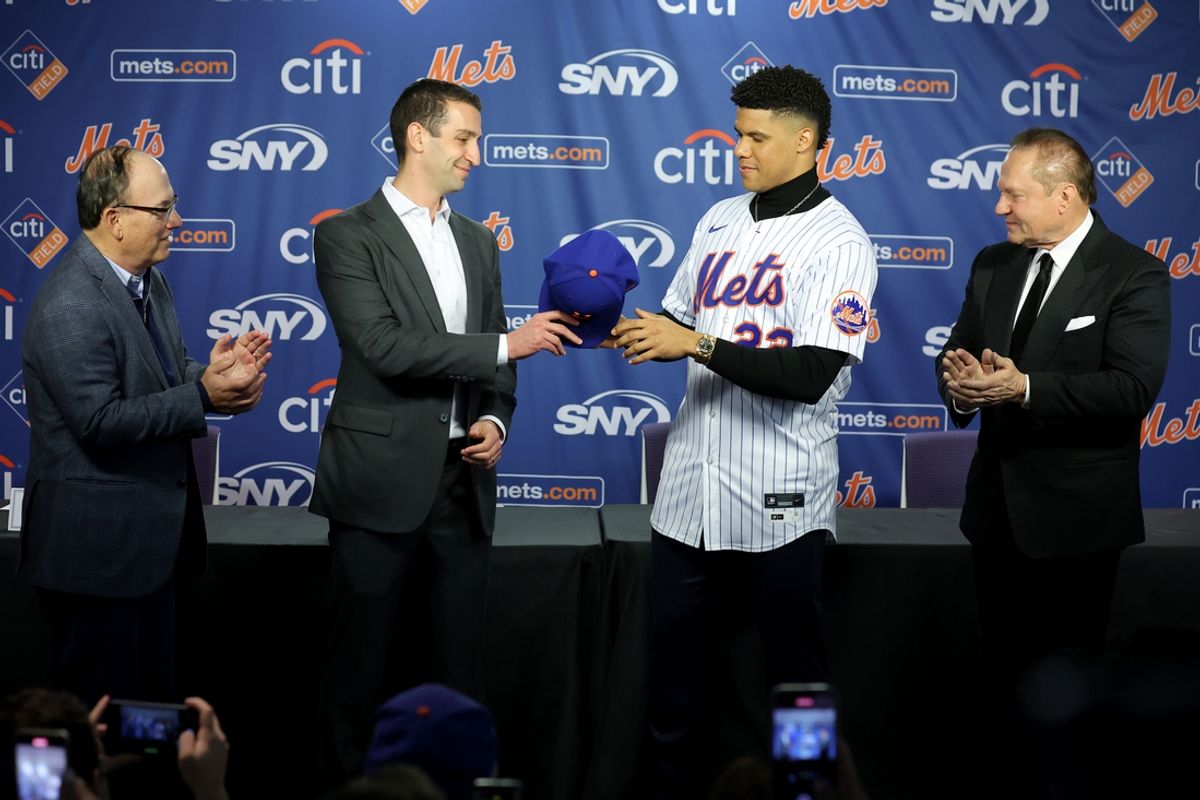 Dec 12, 2024; Flushing, NY, USA; New York Mets general manager David Stearns hands a cap to New York Mets right fielder Juan Soto (22) during Soto's introductory press conference at Citi Field. Also pictured New York Mets owner Steve Cohen (left) and agent Scott Boras (right). Mandatory Credit: Brad Penner-Imagn Images