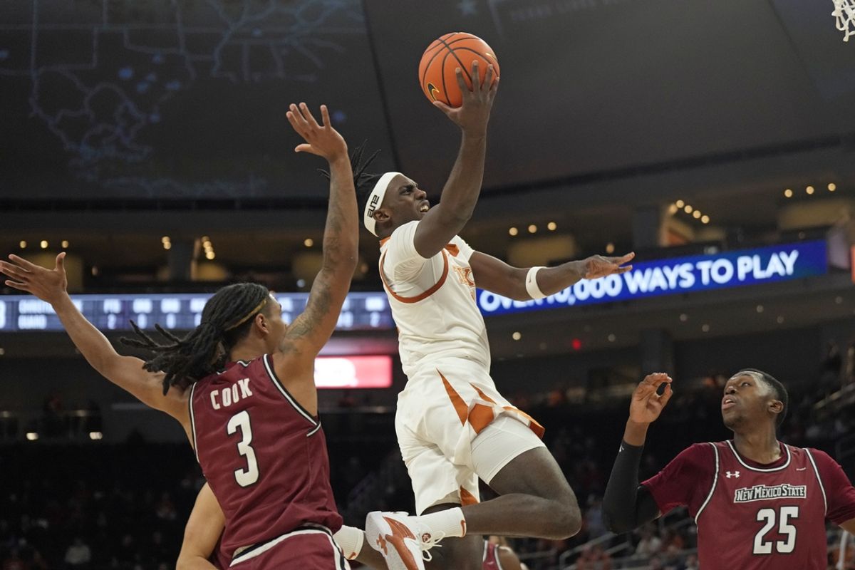 Dec 12, 2024; Austin, Texas, USA; Texas Longhorns forward Arthur Kaluma (6) drives to the basket between New Mexico State Aggies forward Emmanuel Tshimanga (25) and guard Christian Cook (3) during the first half at Moody Center. Mandatory Credit: Scott Wachter-Imagn Images