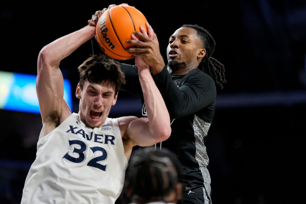 Xavier Musketeers forward Zach Freemantle (32) pulls in a rebound away from Cincinnati Bearcats guard Day Day Thomas (1) in the second half of the 92nd Annual Crosstown Shootout NCAA basketball game between the Cincinnati Bearcats and the Xavier Musketeers at Fifth Third Arena on the UC campus in Cincinnati on Saturday, Dec. 14, 2024. The Bearcats won 68-65.