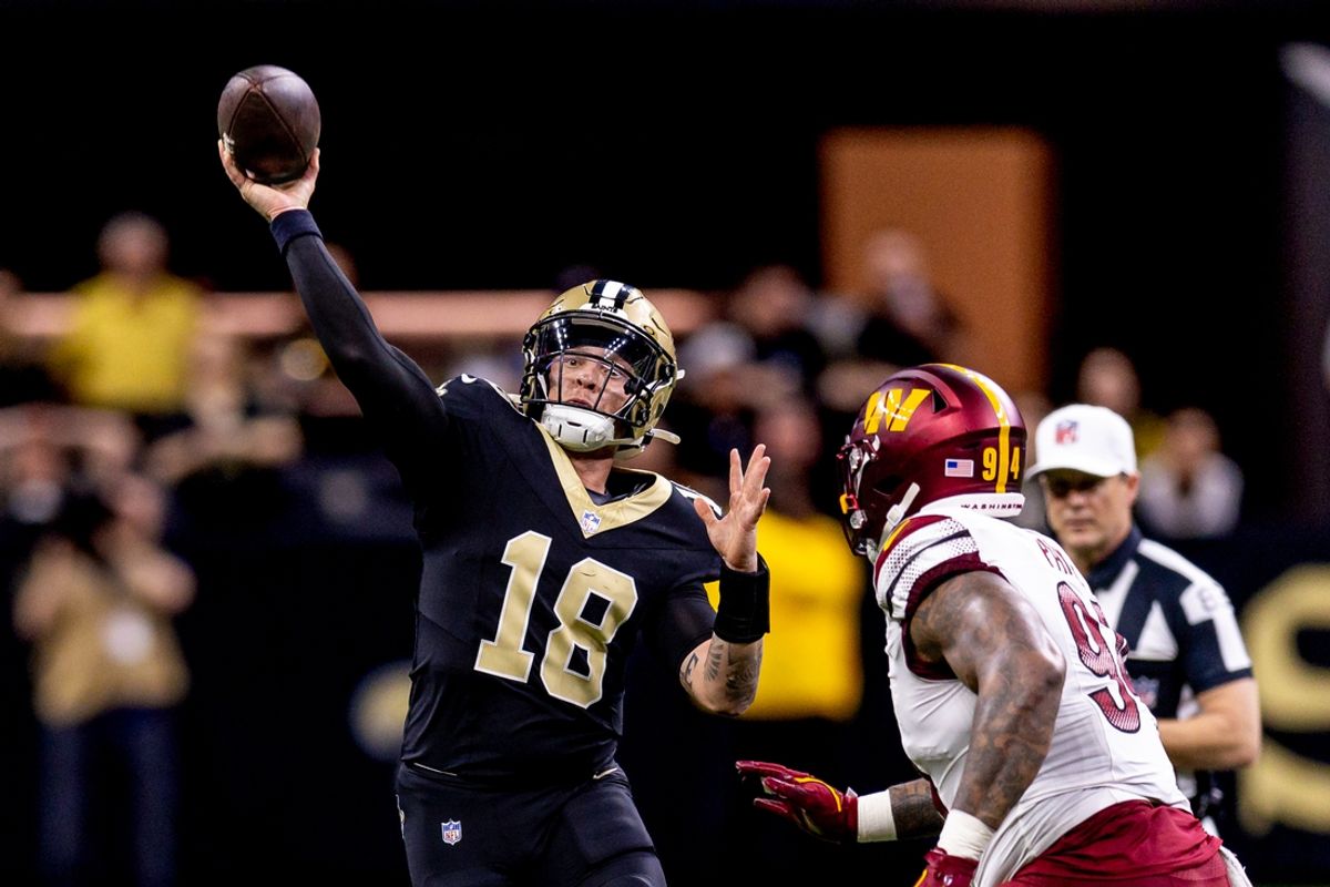 Dec 15, 2024; New Orleans, Louisiana, USA;  New Orleans Saints quarterback Spencer Rattler (18) scrambles against Washington Commanders defensive tackle Daron Payne (94) during the second half at Caesars Superdome. Mandatory Credit: Stephen Lew-Imagn Images
