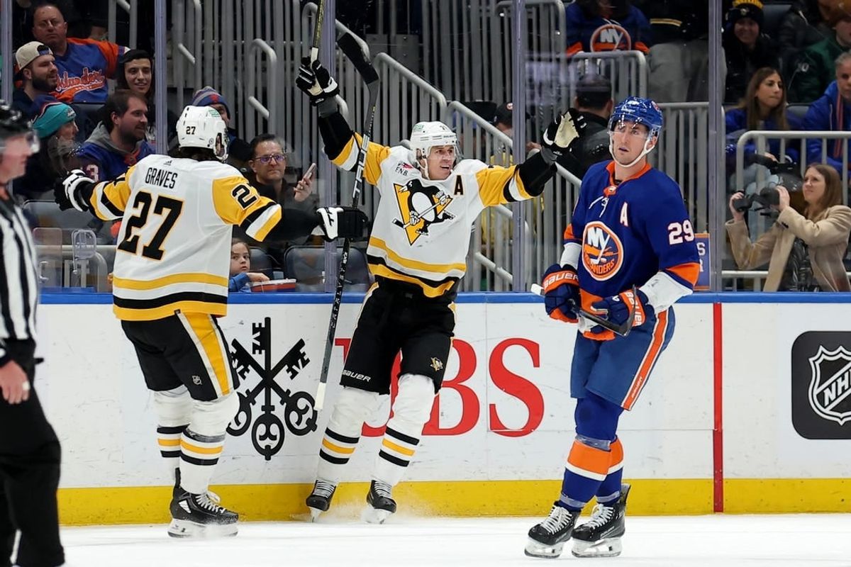 Dec 27, 2023; Elmont, New York, USA; Pittsburgh Penguins center Evgeni Malkin (71) celebrates his goal against the New York Islanders with defenseman Ryan Graves (27) in front of Islanders center Brock Nelson (29) during the second period at UBS Arena.