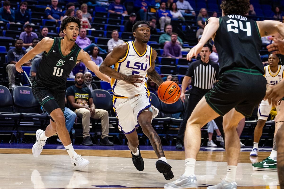 Dec 17, 2024; Baton Rouge, Louisiana, USA;  LSU Tigers guard Cam Carter (5) dribbles against Stetson Hatters guard Tristan Gross (10) and forward Jordan Wood (24) during the first half at Pete Maravich Assembly Center. Mandatory Credit: Stephen Lew-Imagn Images
