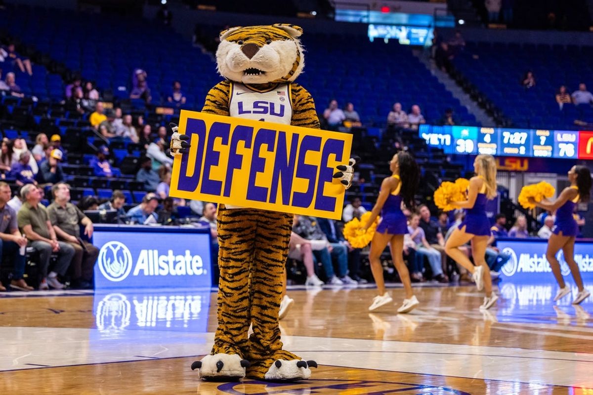 Dec 17, 2024; Baton Rouge, Louisiana, USA;  LSU Tigers mascot Mike the Tiger holds up a defense sign behind the Stetson Hatters team on a time out during the second half at Pete Maravich Assembly Center. Mandatory Credit: Stephen Lew-Imagn Images